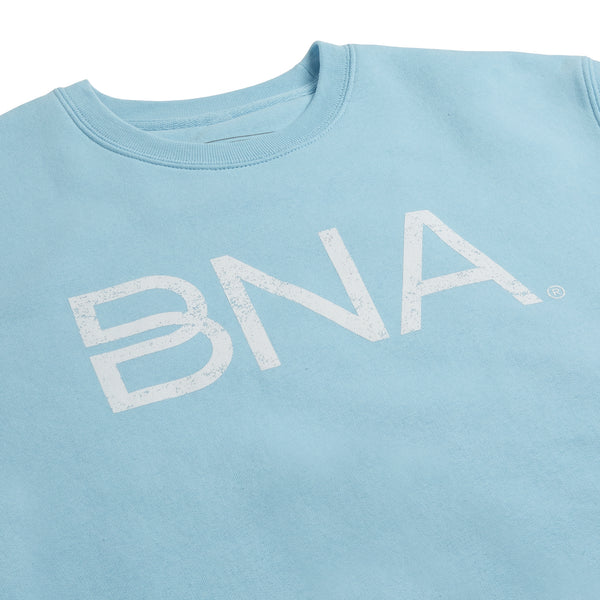 Detail shot of sky blue crewneck sweatshirt with white distressed BNA logo centered on the chest.  BNA logo features a unique infinity "B."